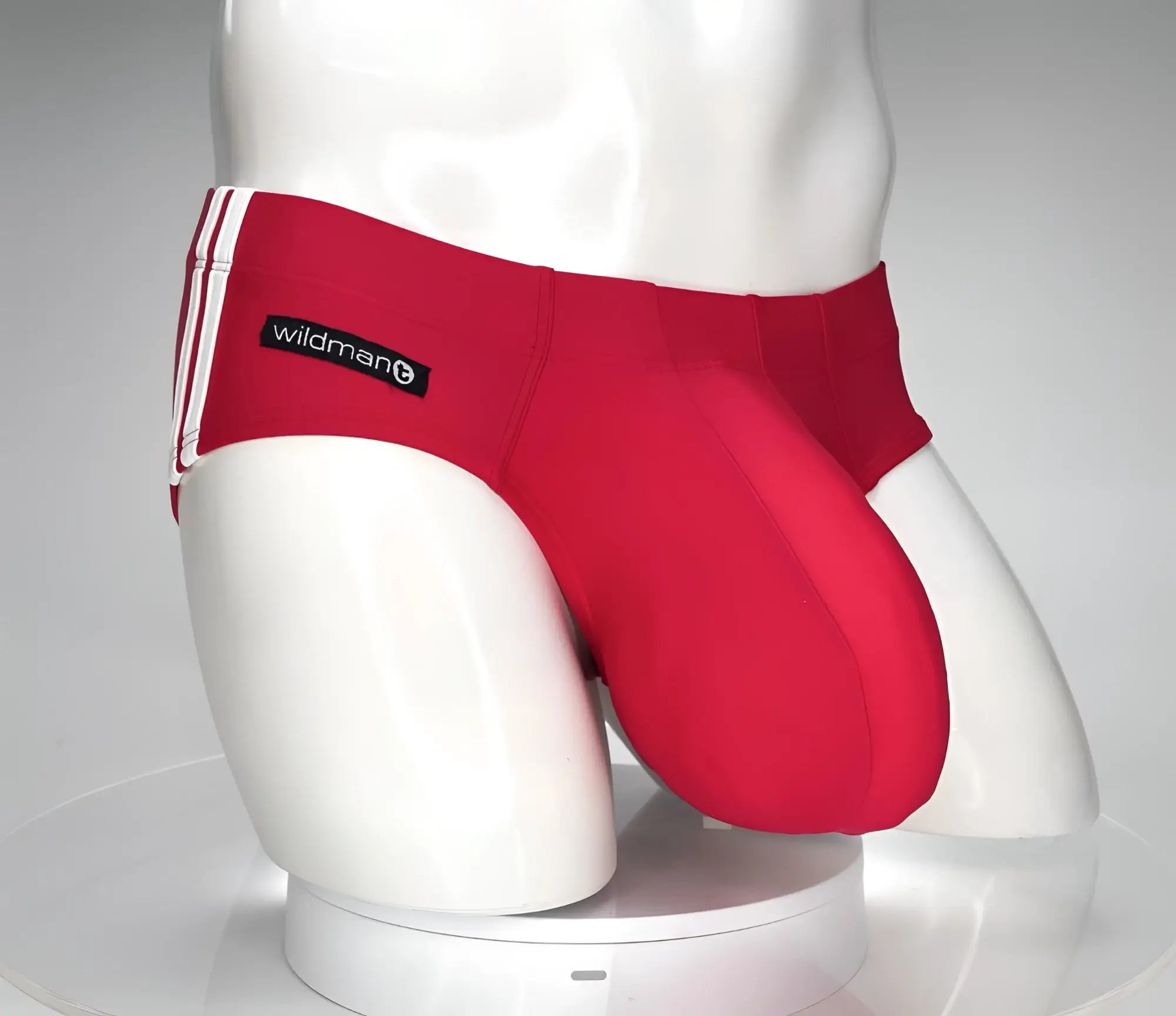 Red WildmanT swim brief with white side stripes and branded label on a white mannequin torso.