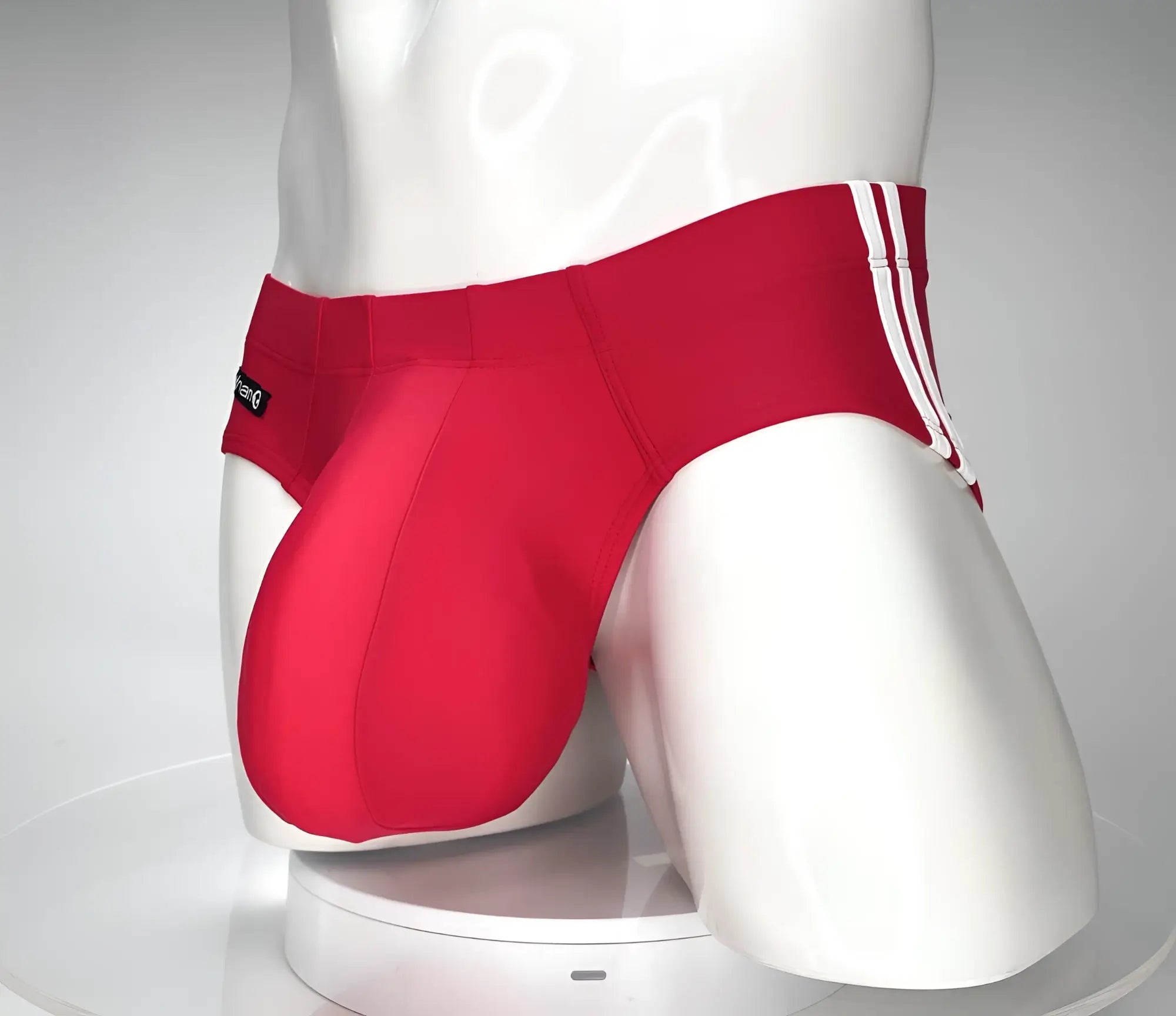 WildmanT red swim brief on a mannequin, featuring a contoured front pouch and white double-side stripes.