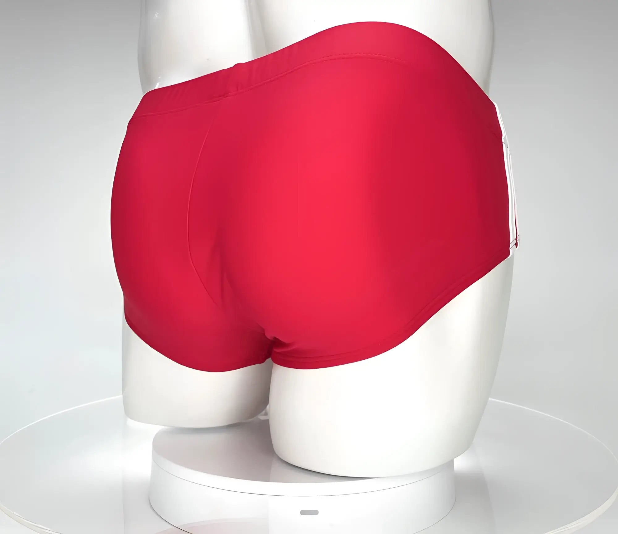 Red WildmanT swim brief viewed from behind on a mannequin, featuring white side accents.