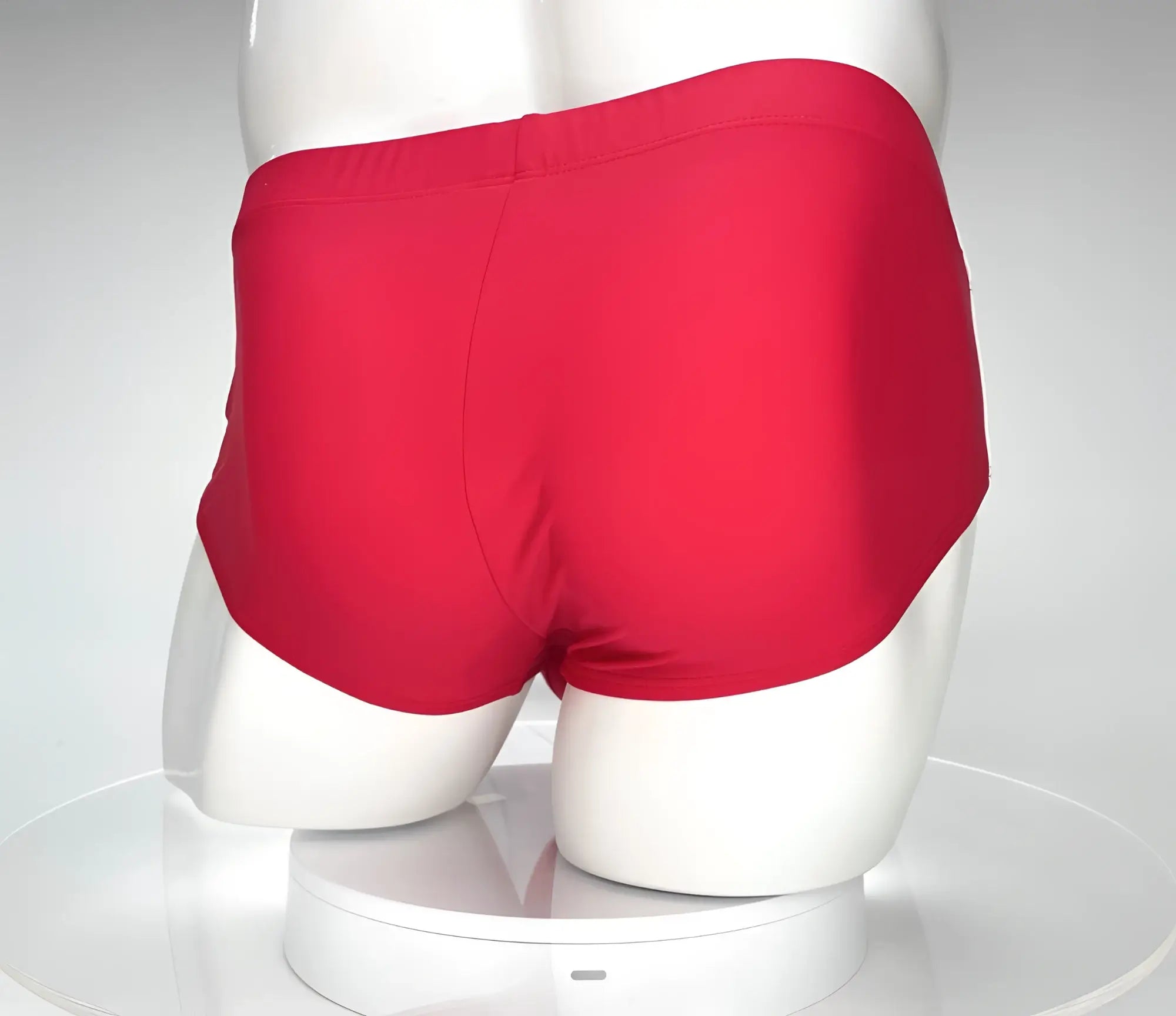 Back view of bright red solid color swim brief on a white mannequin torso against a neutral background.