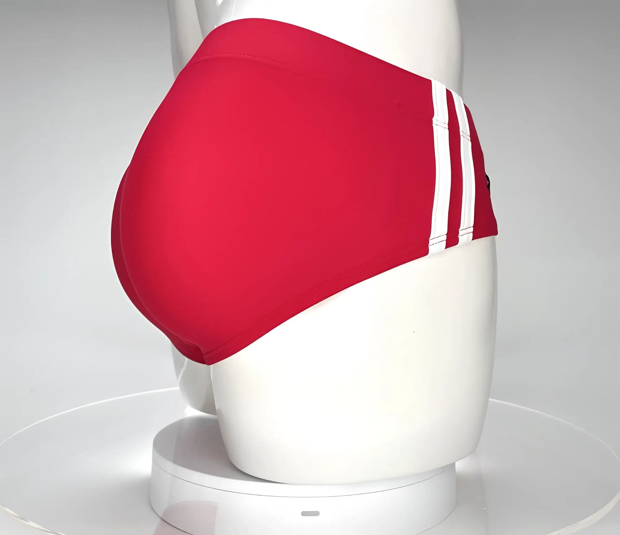 Red swim brief on a mannequin, featuring two white side stripes and a contoured, full-coverage back design.