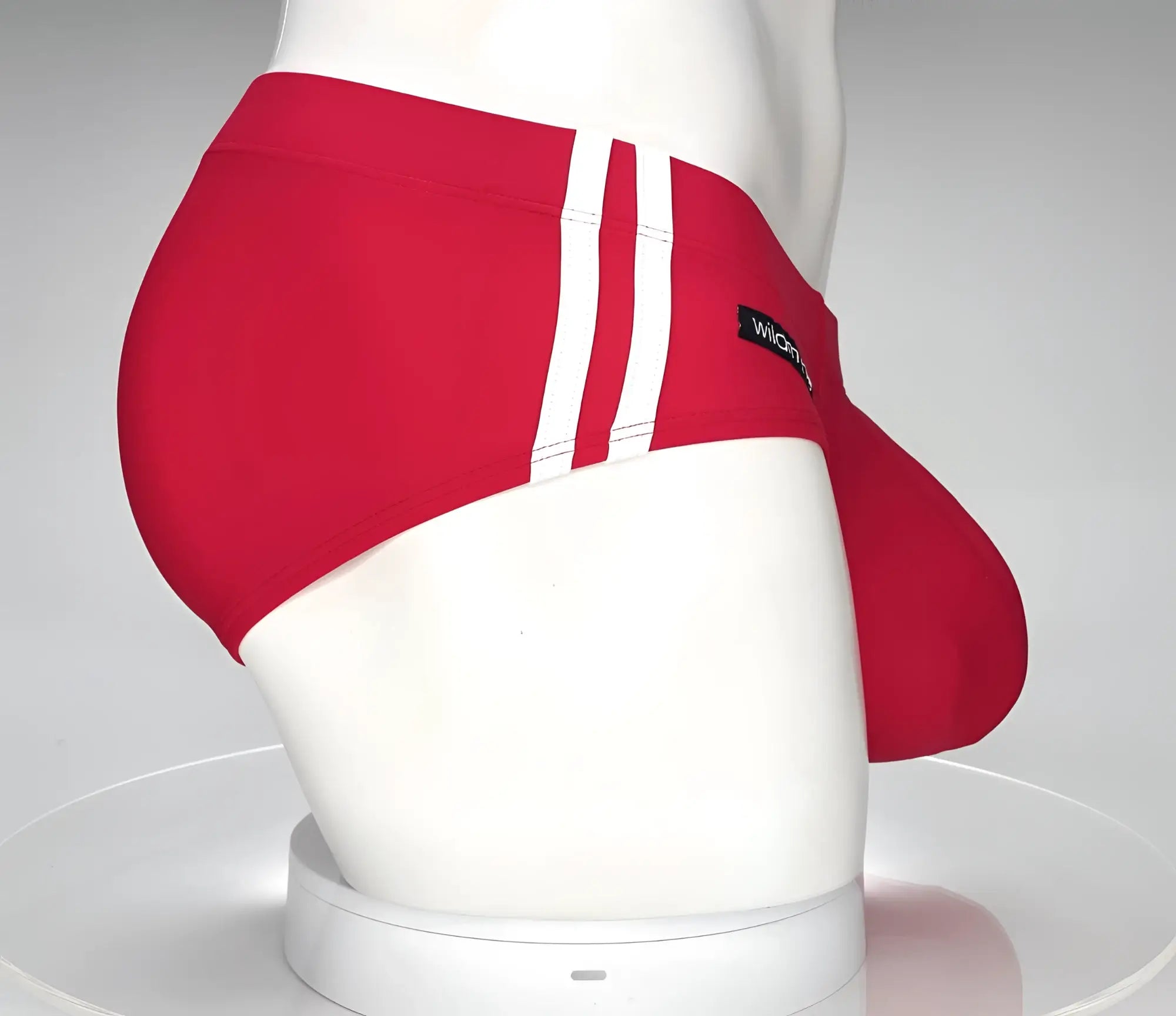 Red swim brief with dual white side stripes and a prominent contoured pouch on a white mannequin.