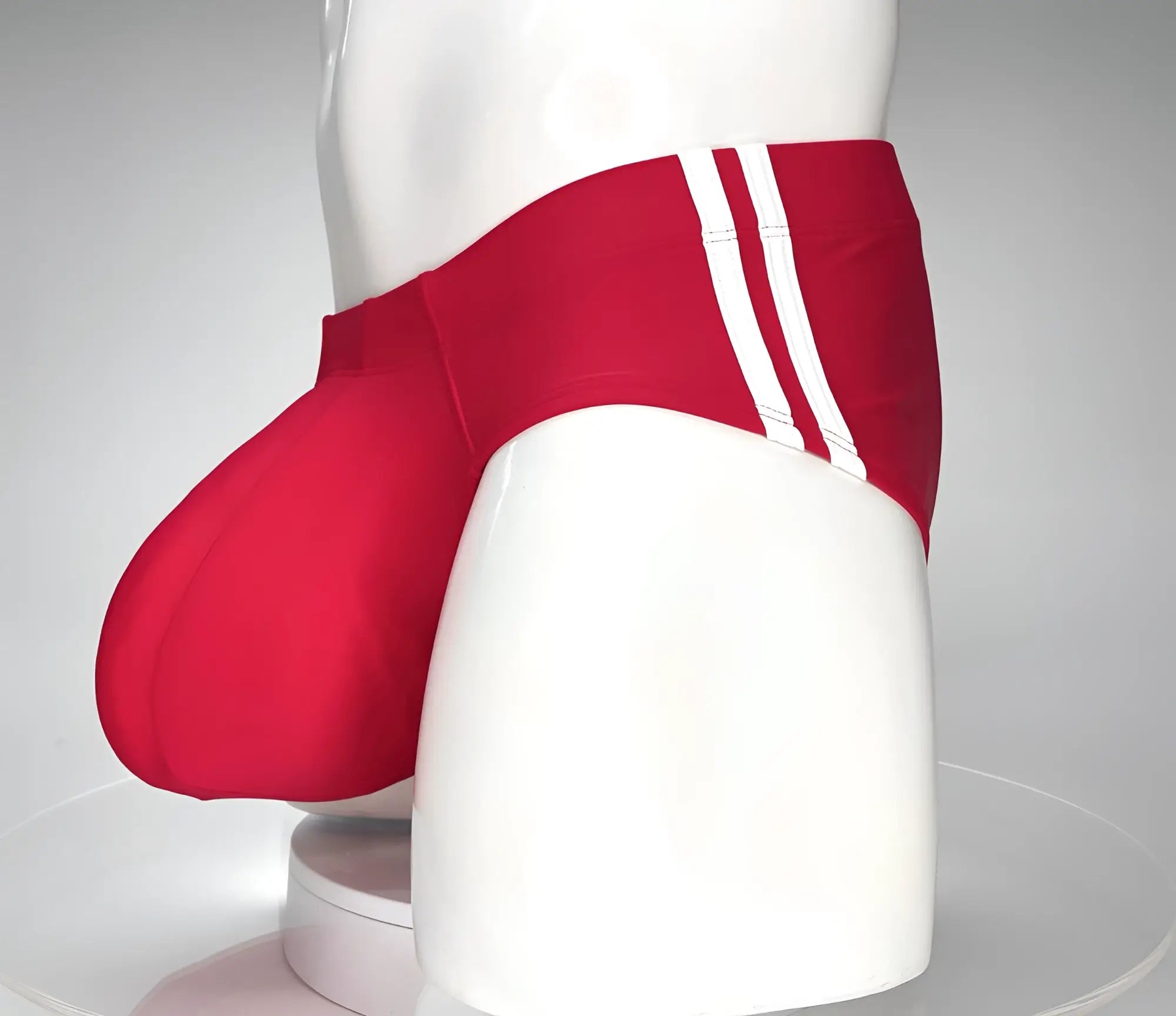 Red WildmanT swim brief with a prominent contoured pouch and double white side stripes on a white mannequin torso.