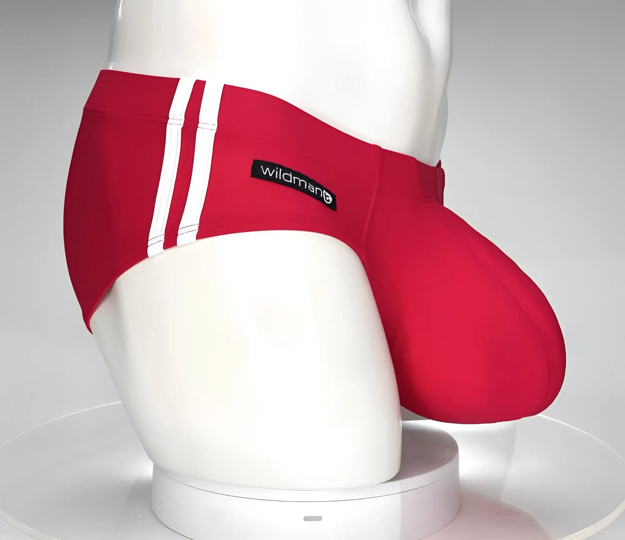 Red swim brief with dual white side stripes and a prominent contoured pouch, featuring a WildmanT logo tag.