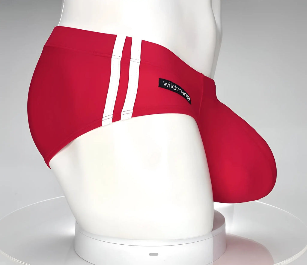 Red WildmanT swim brief with white side stripes and black brand tag on a white mannequin torso.