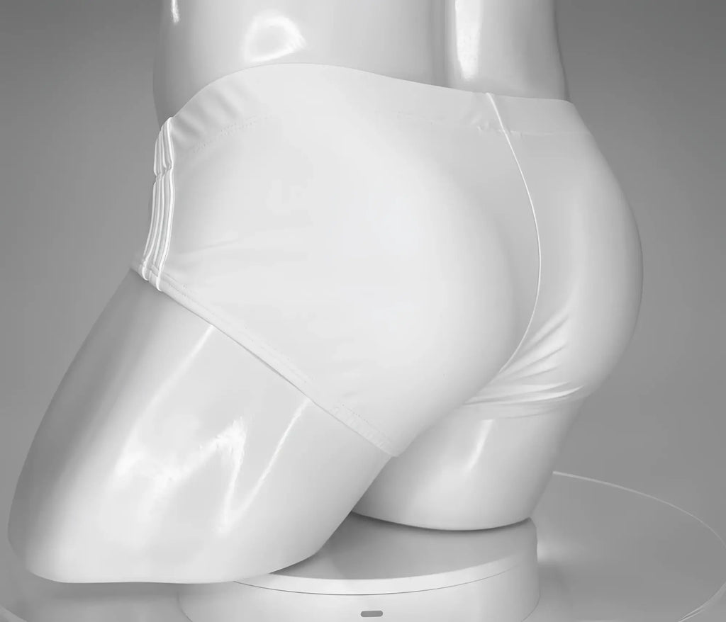White WildmanT swim brief worn on a glossy white male mannequin, shown from a rear three-quarter angle.