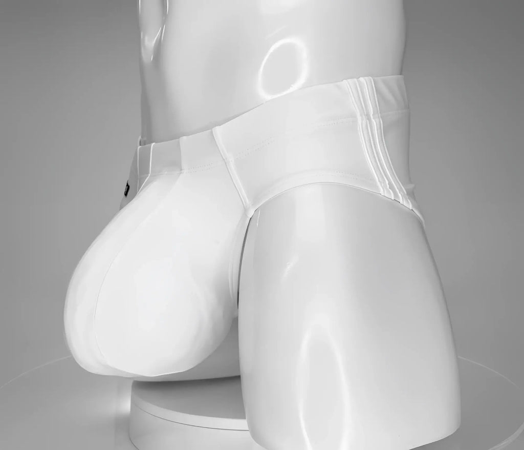 White low-rise swim brief with a large, contoured front pouch on a mannequin torso against a gray background.