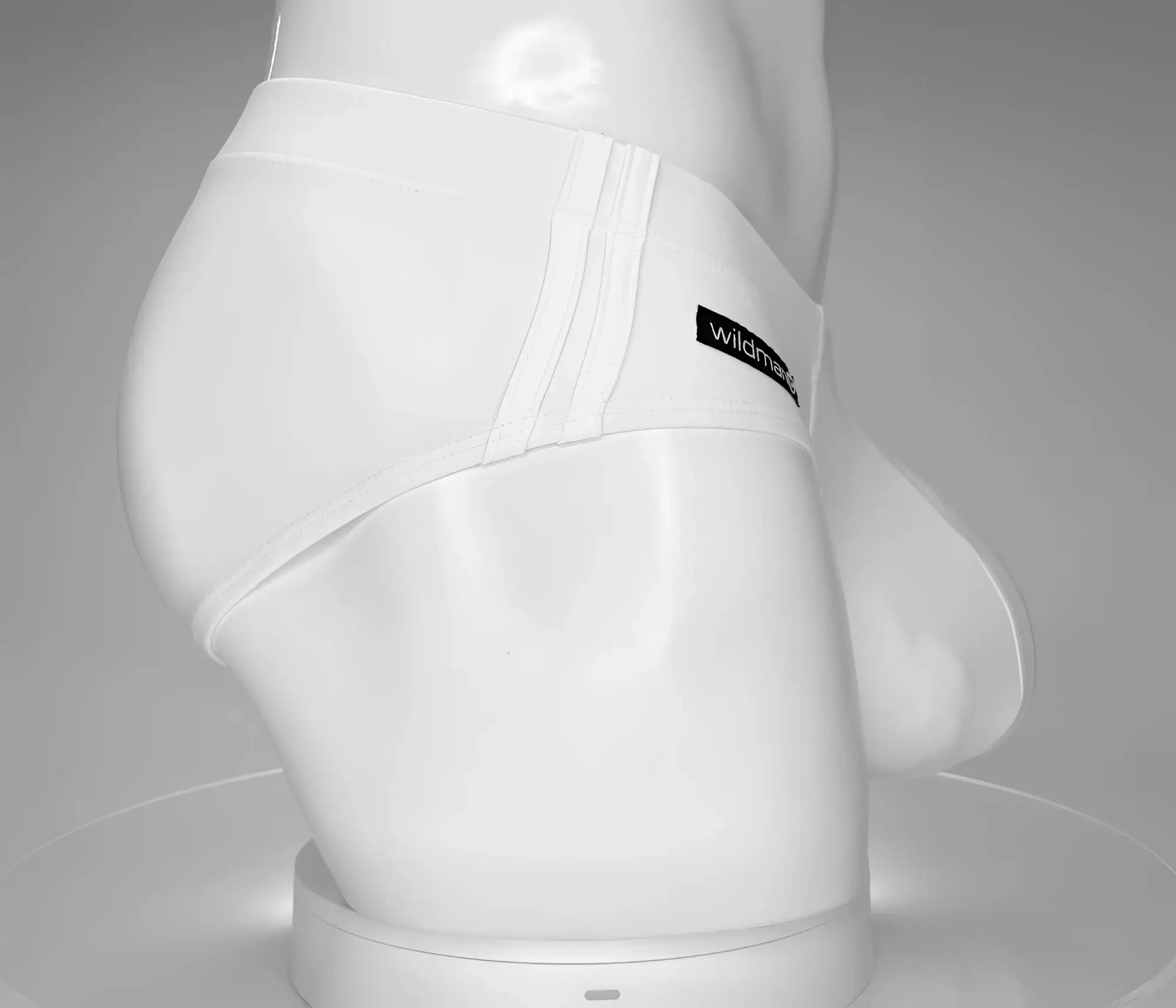 White WildmanT swim brief on a mannequin, featuring triple-stitched side detail and a black logo tag.