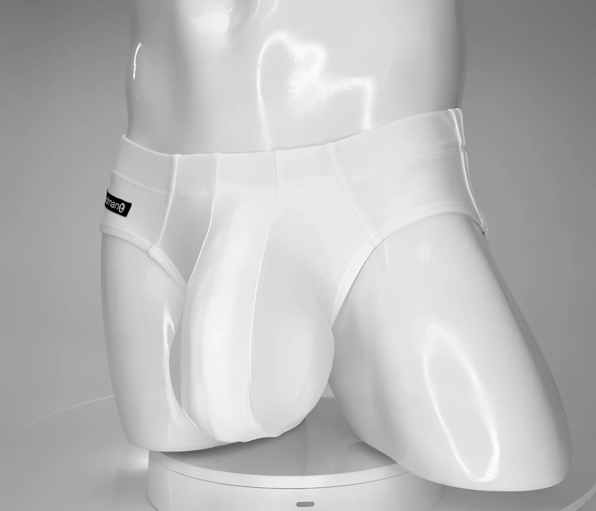 White WildmanT swim brief with a contoured pouch design, shown on a mannequin torso with a branded tag on the hip.