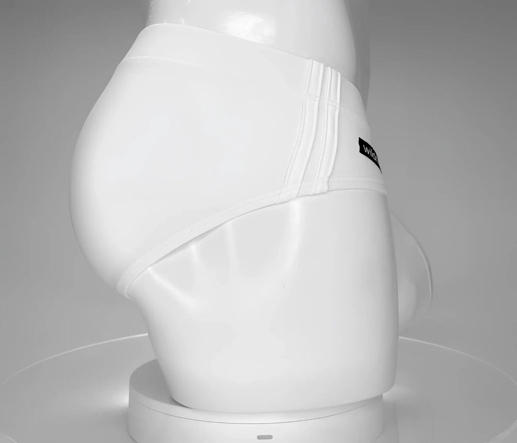 Side view of a white WildmanT swim brief on a mannequin, featuring ribbed side detailing and a small logo tag.