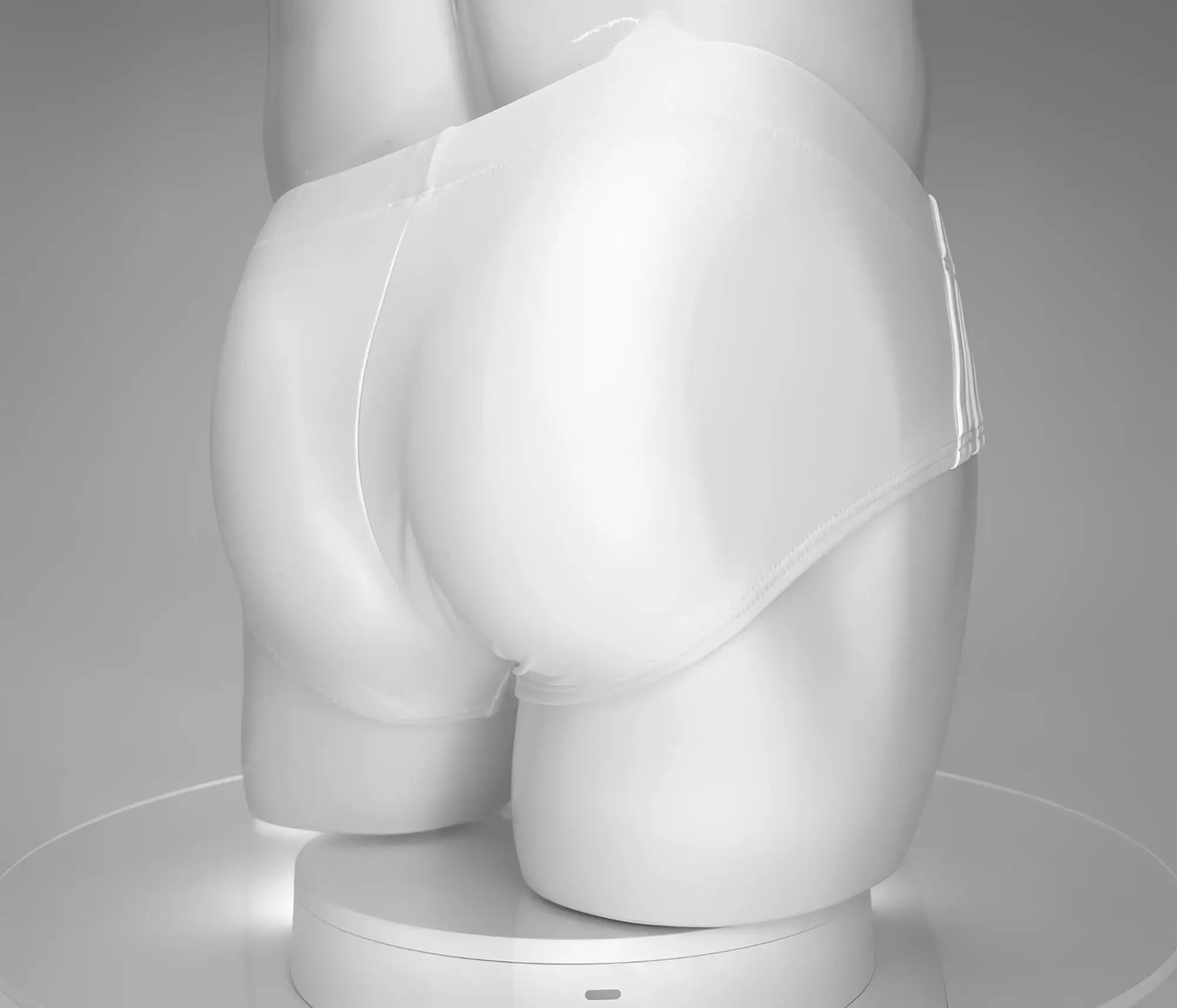 Rear view of a white, low-rise WildmanT swim brief worn by a male mannequin against a grey studio background.