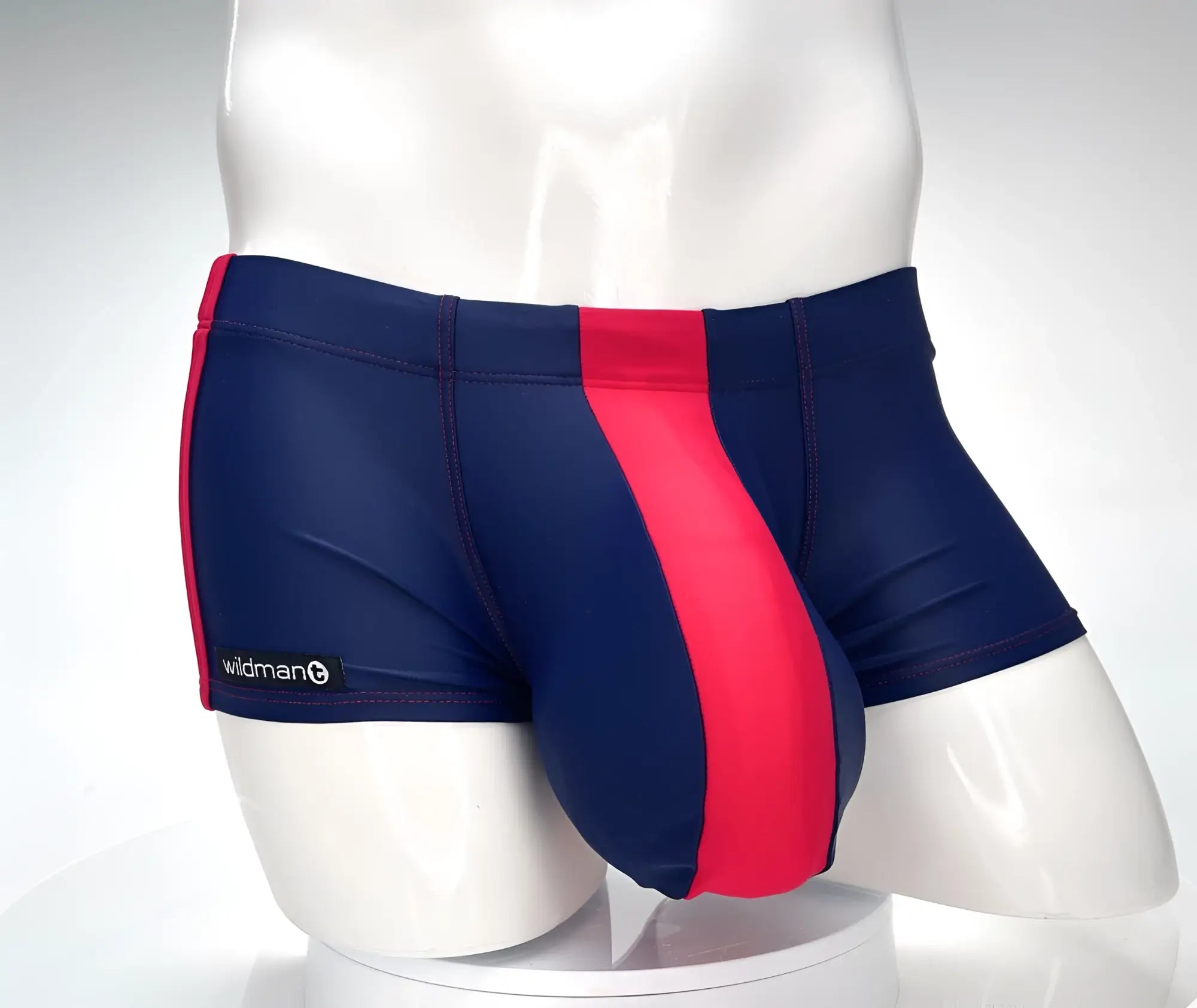 WildmanT navy blue square-cut swim trunks featuring a prominent red front panel and red side stripe on a mannequin.