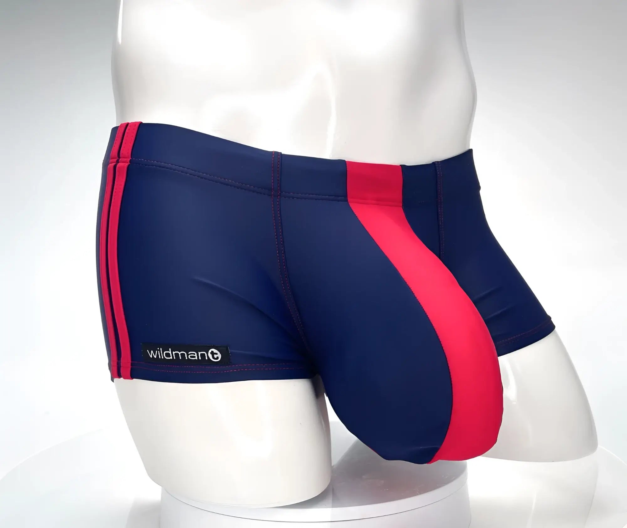Navy and red square-cut swim trunks on a mannequin, featuring a bold red center panel, side stripes, and WildmanT tag.