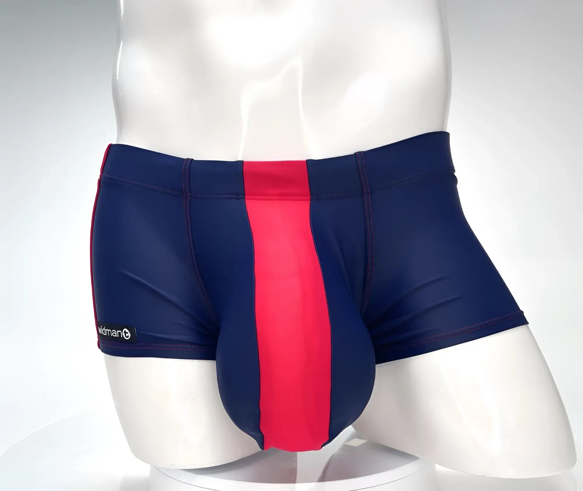 WildmanT navy square-cut swim trunks with a prominent red center panel and red stitching on a mannequin torso.