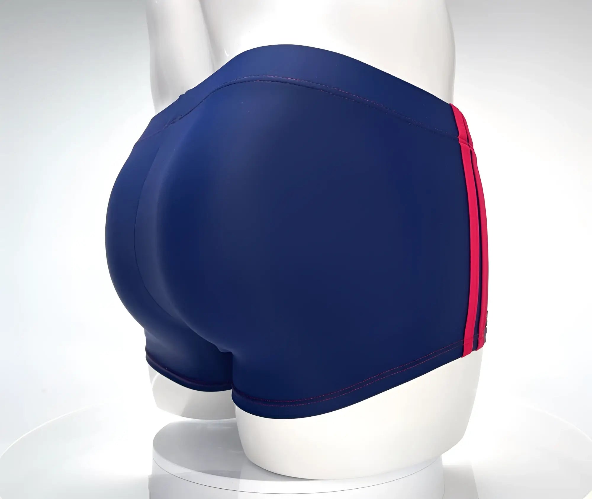 WildmanT navy square-cut swim trunks with red side stripes and red stitching on a white mannequin torso.