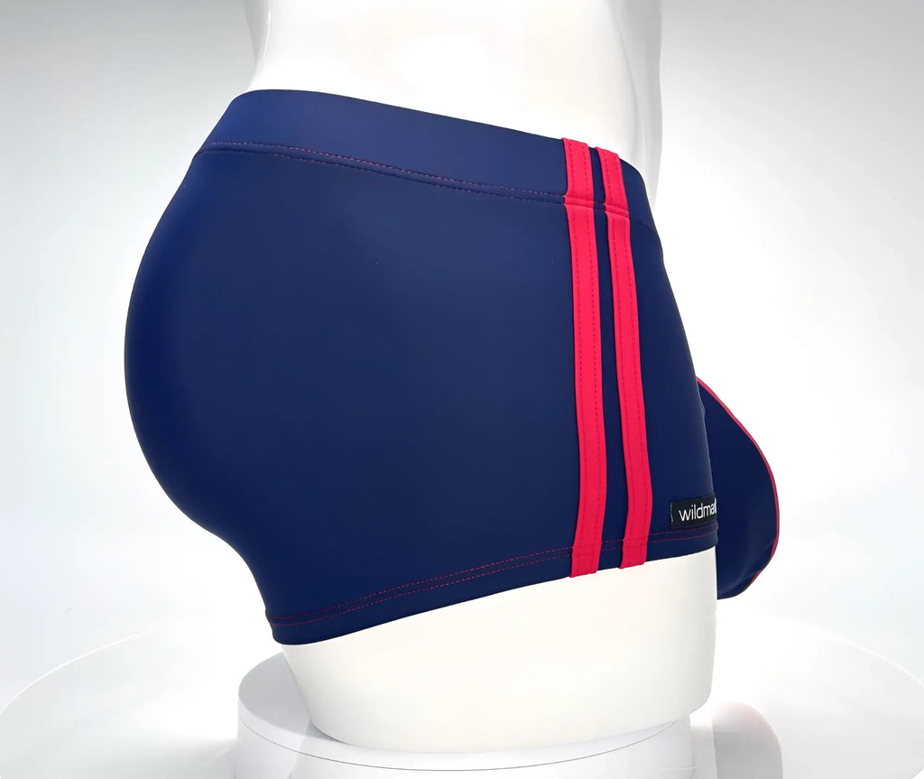 Navy blue square-cut swim trunks with two red side stripes, red stitching, and a WildmanT logo tag on a mannequin.