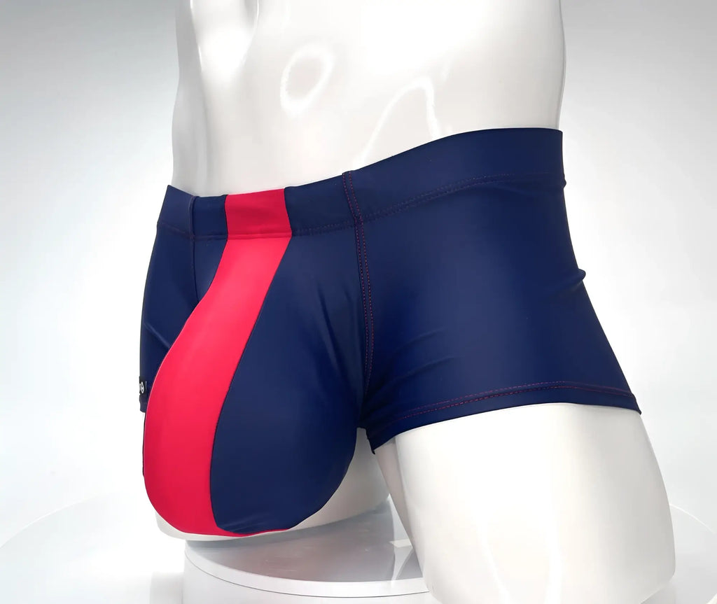 Navy blue WildmanT square-cut swim trunks with a prominent red vertical front panel and red contrast stitching.