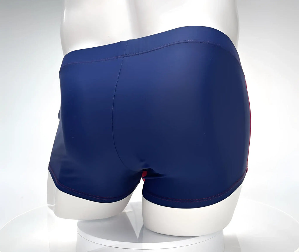 Rear view of navy blue square-cut swim trunks with red contrast stitching, shown on a white mannequin.