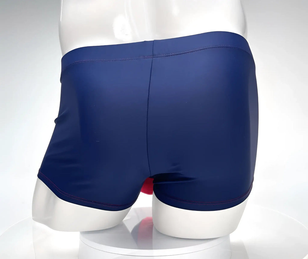 Navy blue square-cut swim trunks with red contrast stitching, shown from the back on a white mannequin.