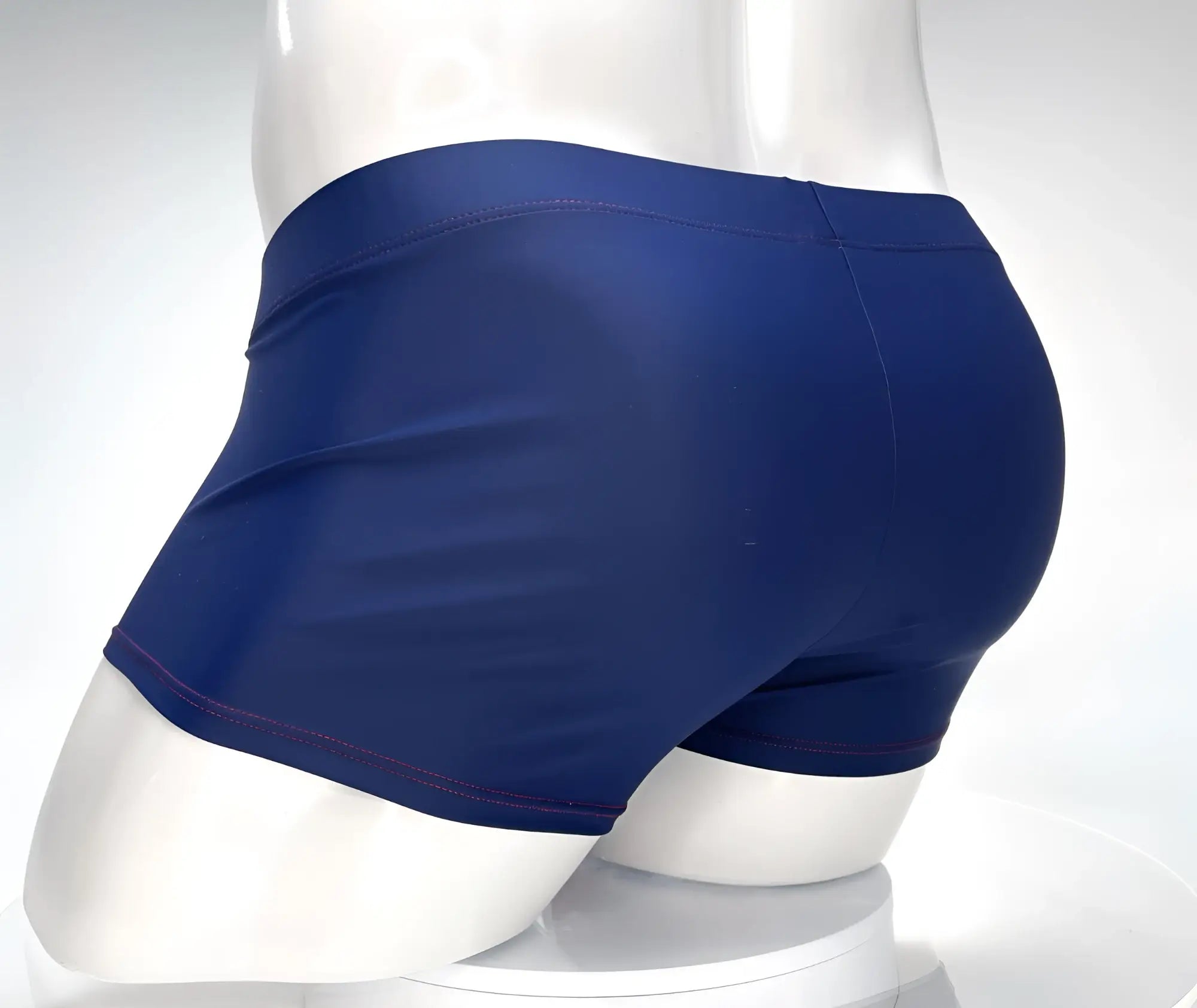 Navy blue swim square cut trunks with red contrast stitching, shown from the side on a white mannequin.