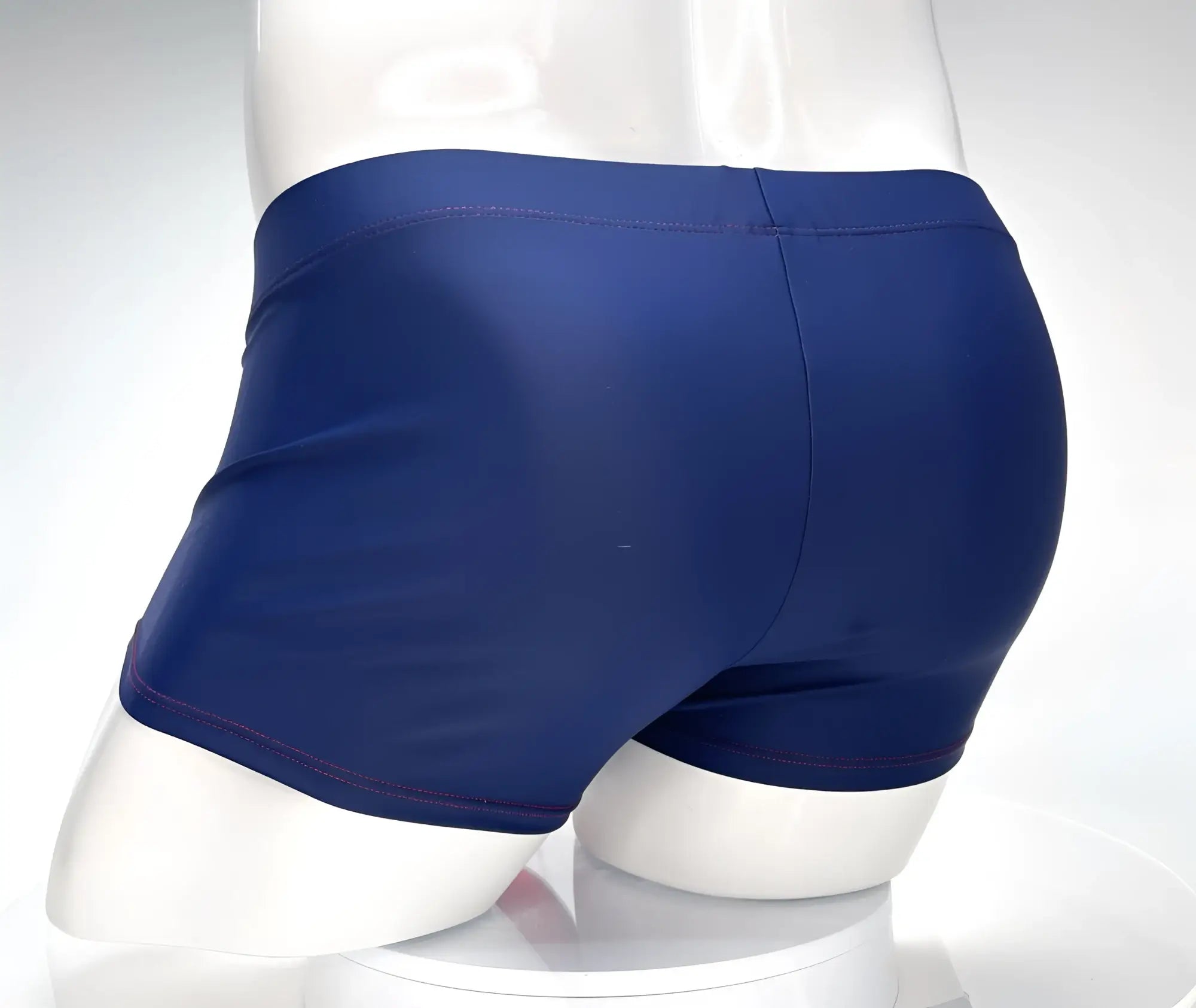 Navy blue WildmanT square-cut swim trunks on a mannequin, featuring contrast red stitching detail.