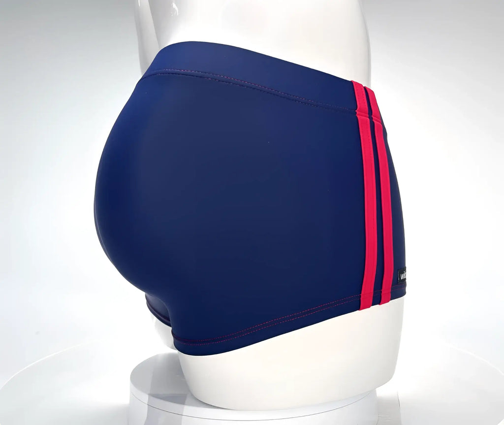 Navy blue square-cut swim trunks with double red side stripes and red contrast stitching on a mannequin.