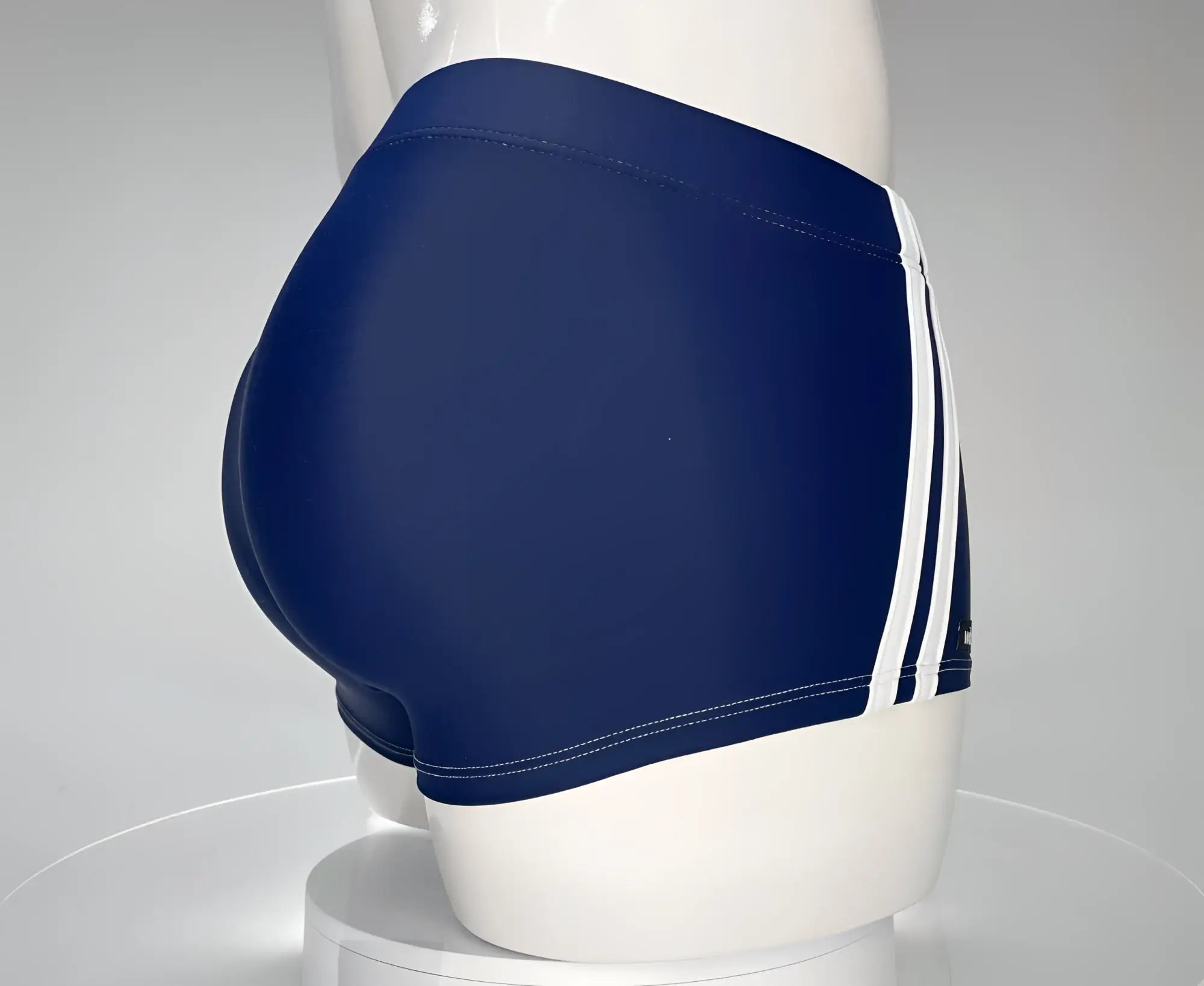 Navy blue WildmanT square-cut swim trunks with white side stripes worn by a mannequin.