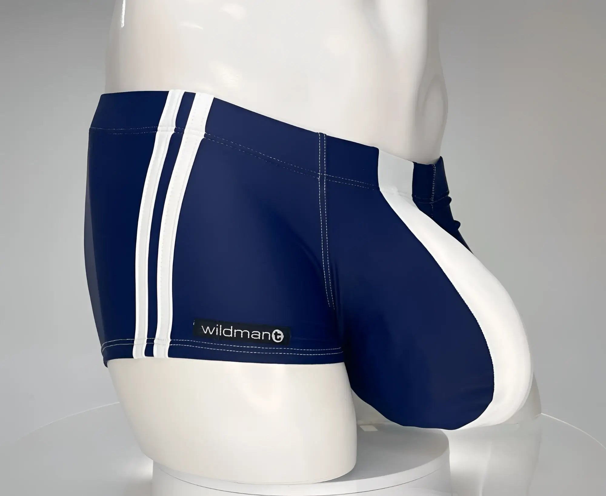 Navy blue square-cut swim trunks with white side stripes and a white front pouch, featuring a WildmanT logo label.