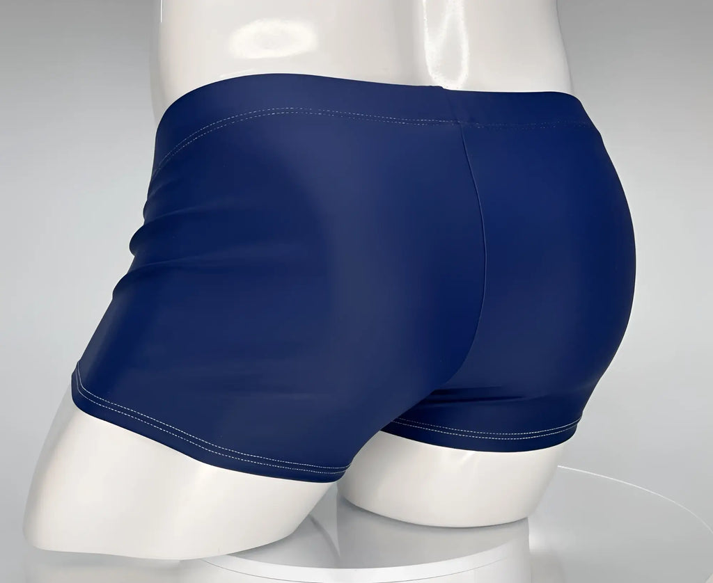 Rear view of navy blue square-cut swim trunks with white contrast stitching on a white mannequin.