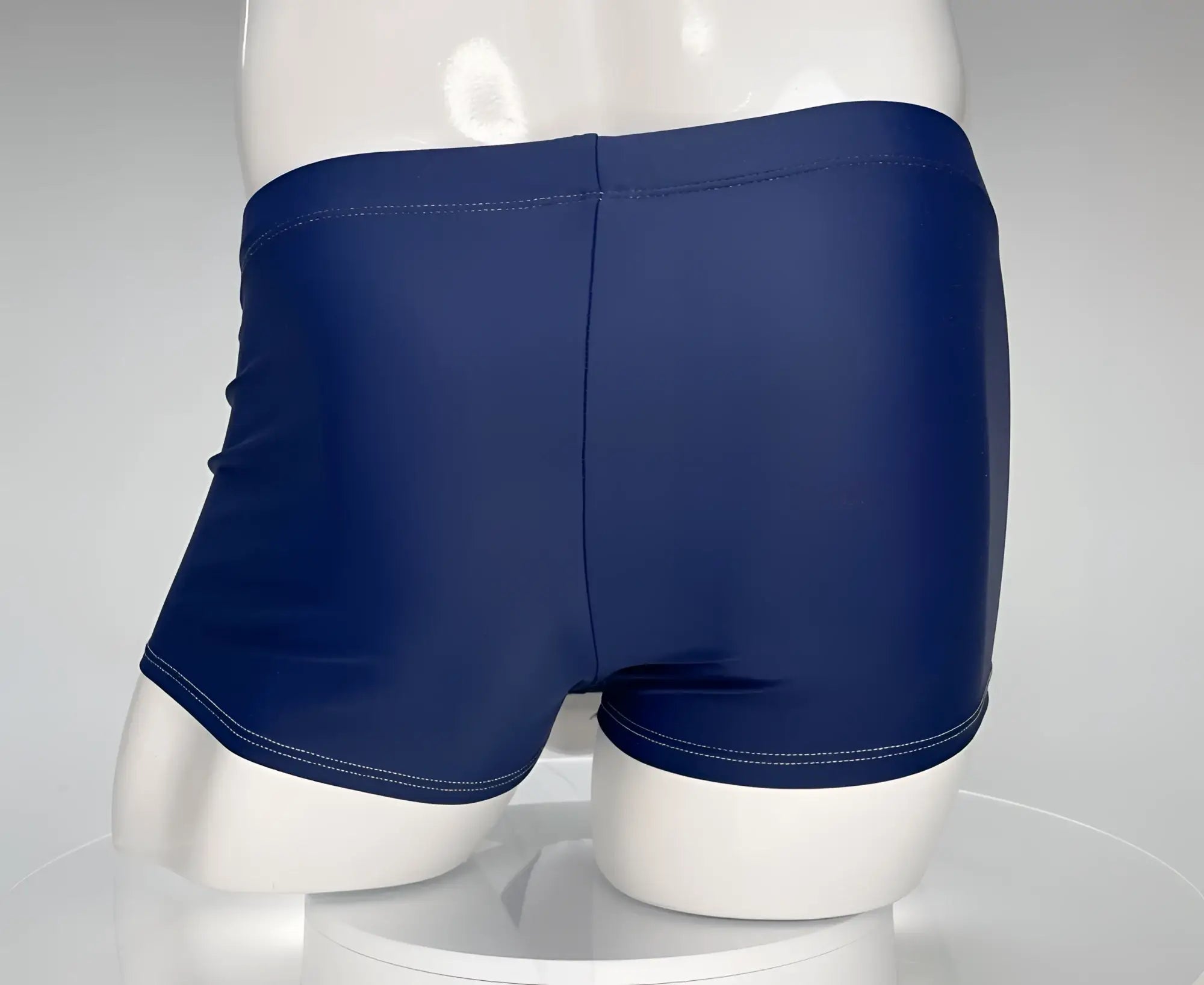 WildmanT navy blue square-cut swim trunks on a white mannequin, featuring a center seam and white contrast stitching.