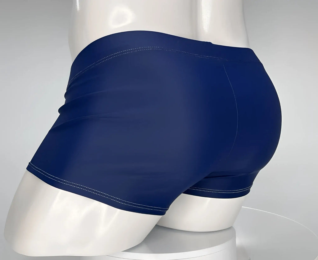 WildmanT navy blue square-cut swim trunks on a white mannequin, showing a rear view with contrasting white stitching.