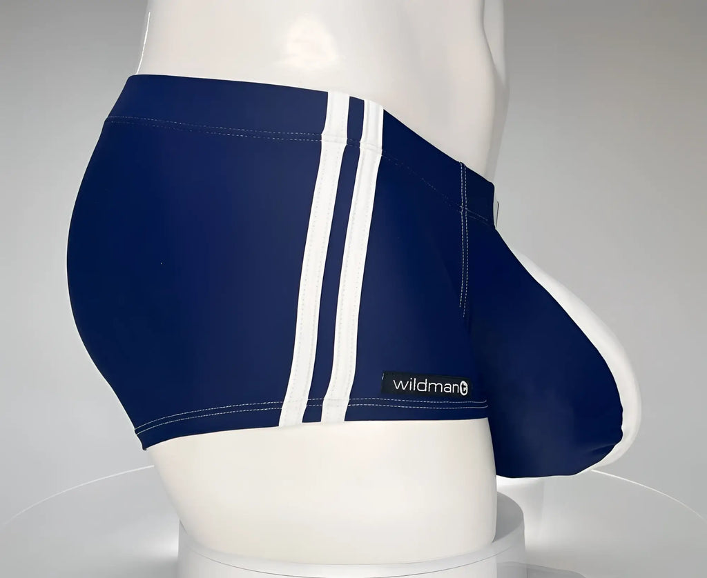Navy blue square cut swim trunks with two white side stripes and a WildmanT logo tag on a white mannequin torso.