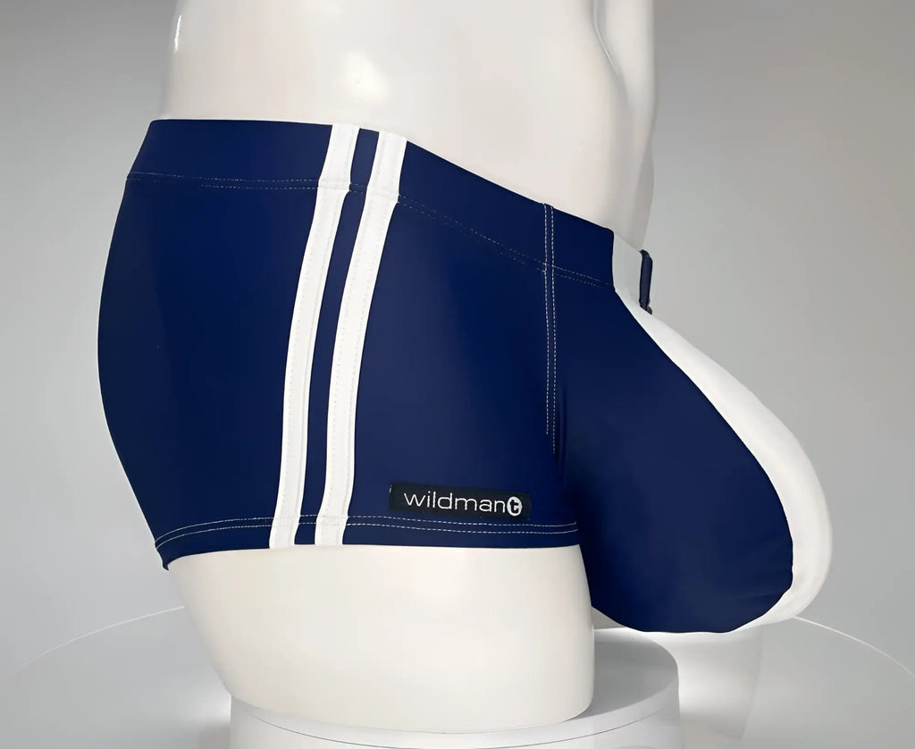 Navy and white WildmanT square-cut swim trunks with side stripes and a contoured pouch on a mannequin torso.
