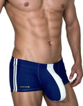 WildmanT navy and white square-cut swim trunks with side stripes and a white front pouch on a muscular man.