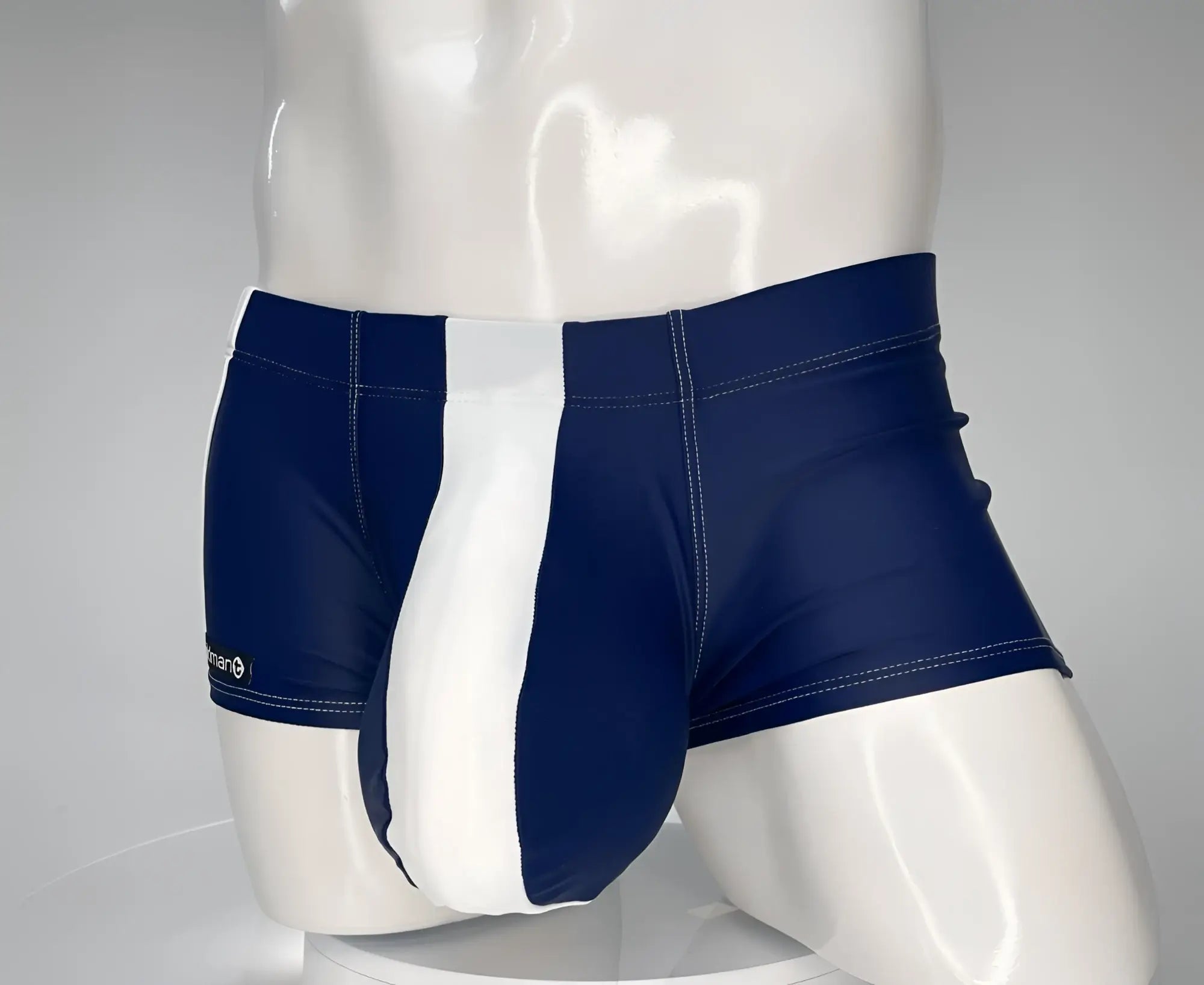 Navy blue and white square-cut swim trunks with a prominent center panel on a white mannequin torso.