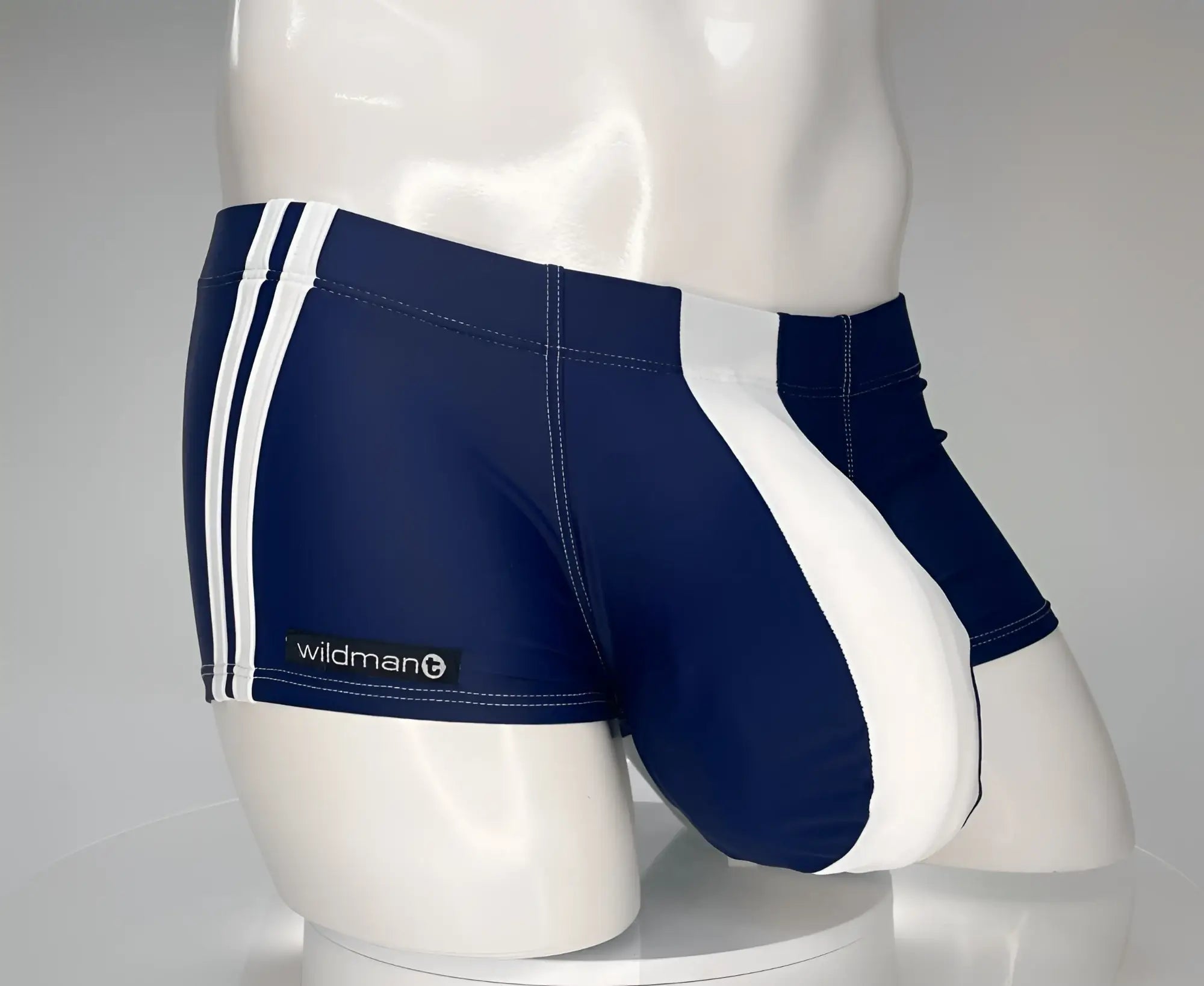 Navy blue and white square-cut swim trunks with double side stripes and a prominent white front pouch on a mannequin.