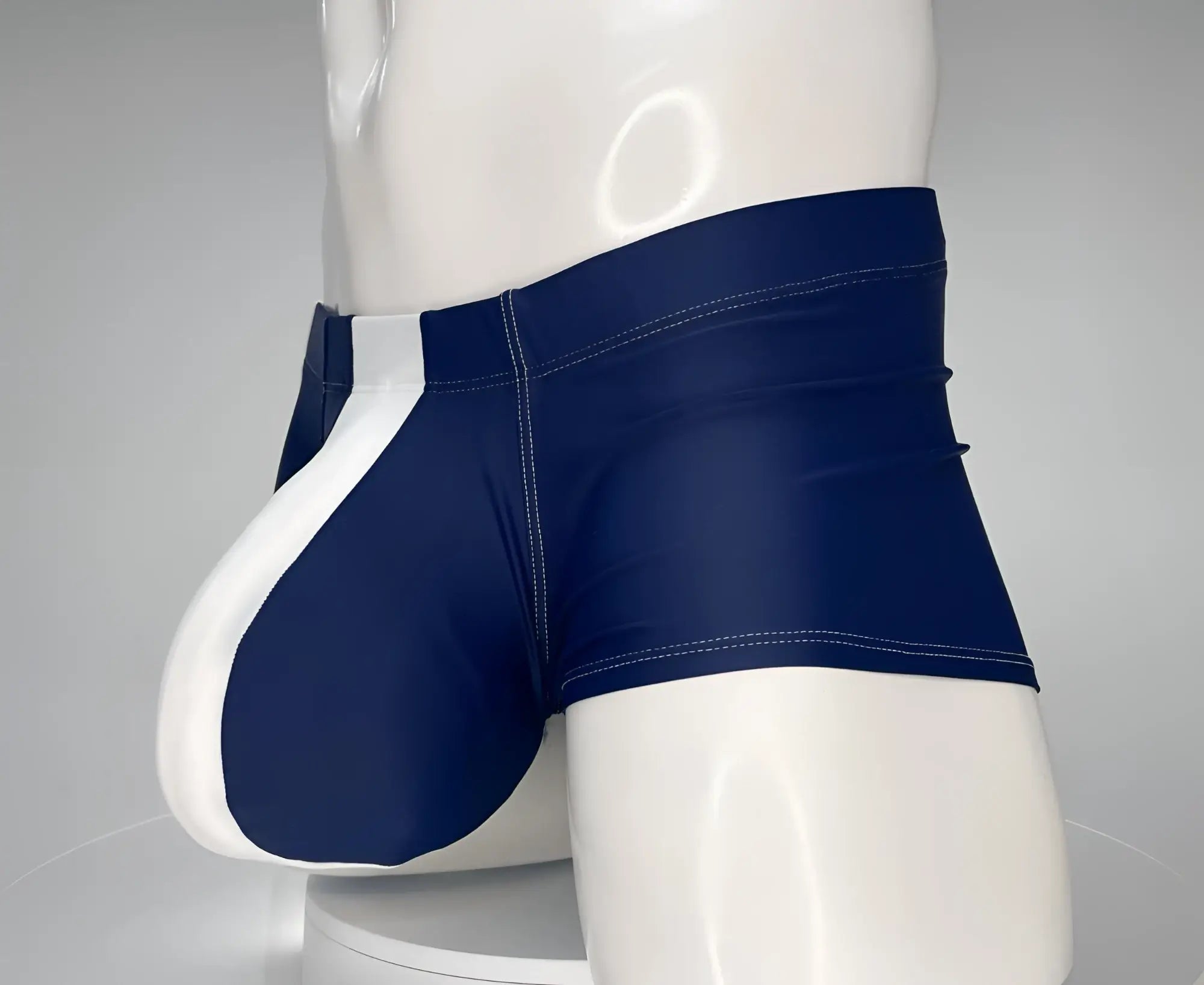 Navy and white square-cut swim trunks with a distinct front pouch, worn on a mannequin.