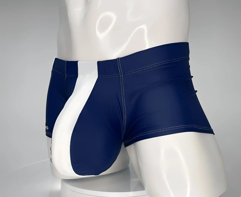 WildmanT square cut swim trunks in navy blue with a prominent white vertical front panel on a white mannequin.