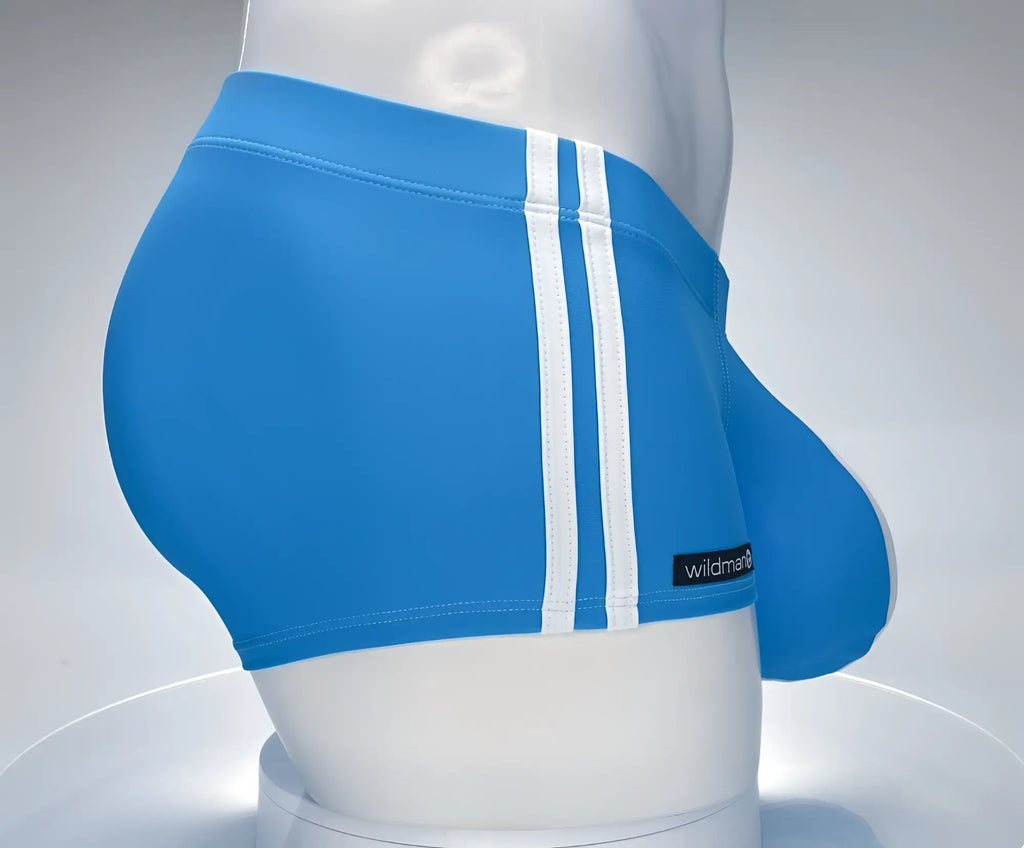 Teal square-cut swim trunks on a mannequin, featuring dual white side stripes and a "wildman" brand patch.