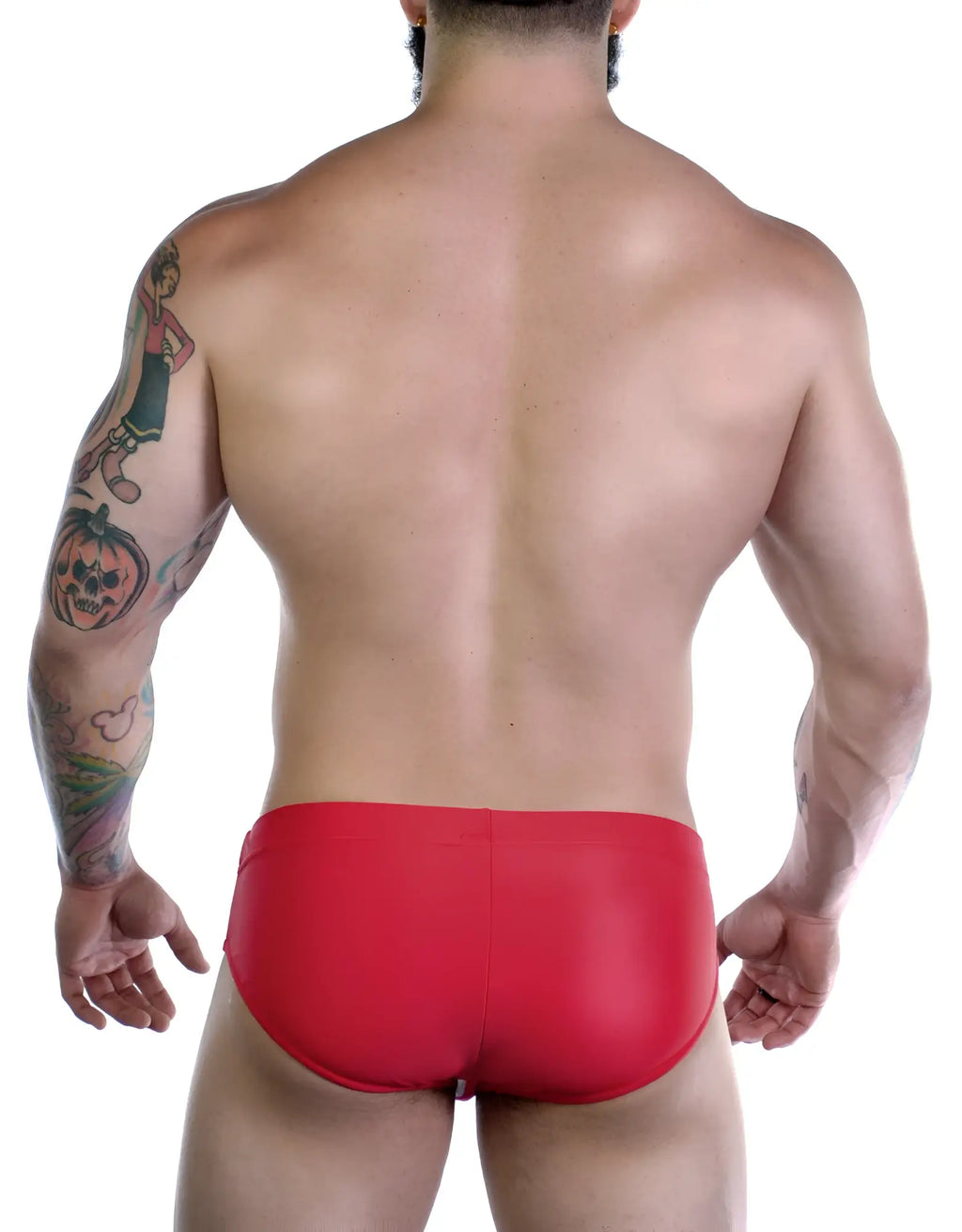 Back view of a muscular man wearing red Sportivo bikini swimwear with visible arm tattoos against a white background.