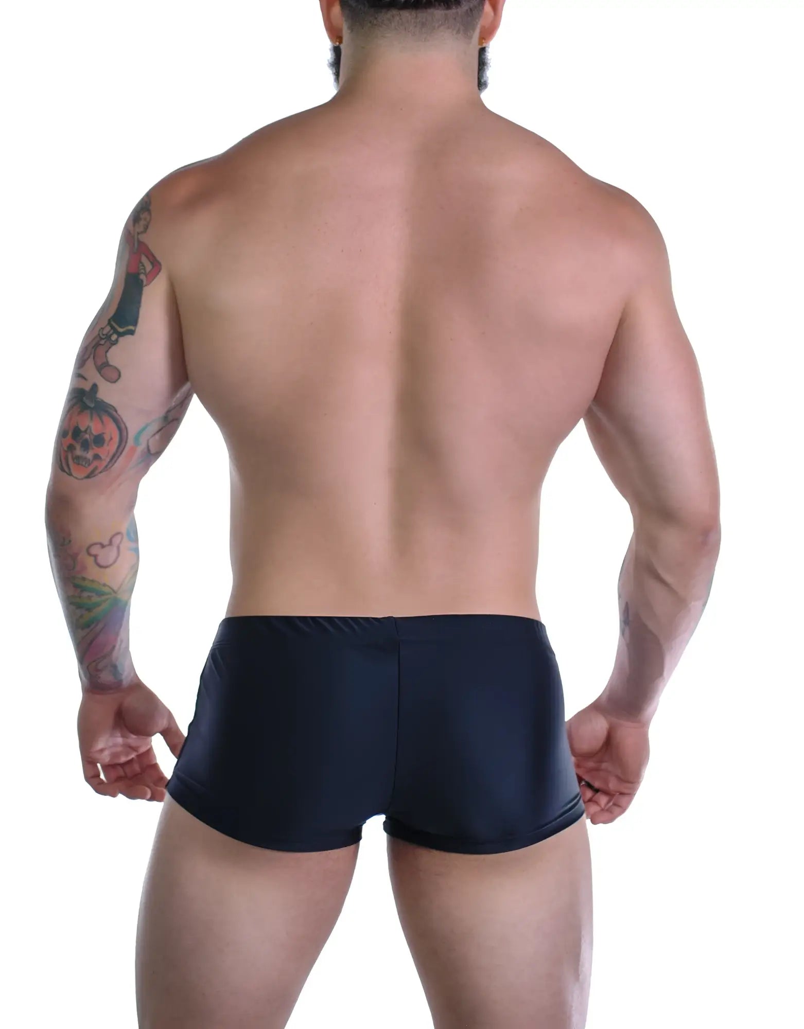 Back view of a muscular man wearing black square-cut swim trunks with purple trim.