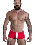 Sportivo Square Cut red swim trunks featuring a vertical white and black stripe detail on a muscular, tattooed man.