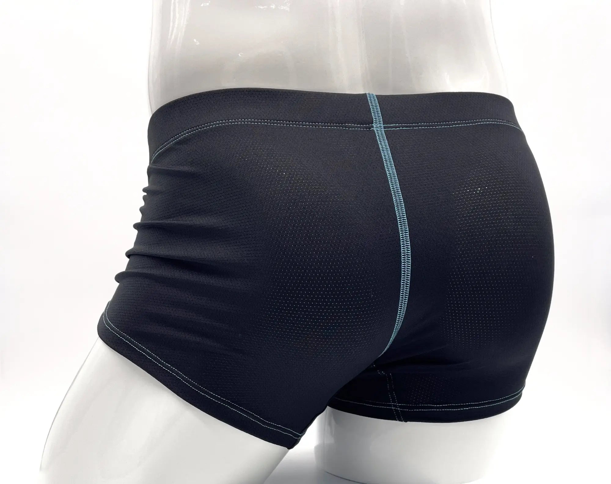 Black perforated boxer briefs on a mannequin with contrasting light blue stitching down the back.
