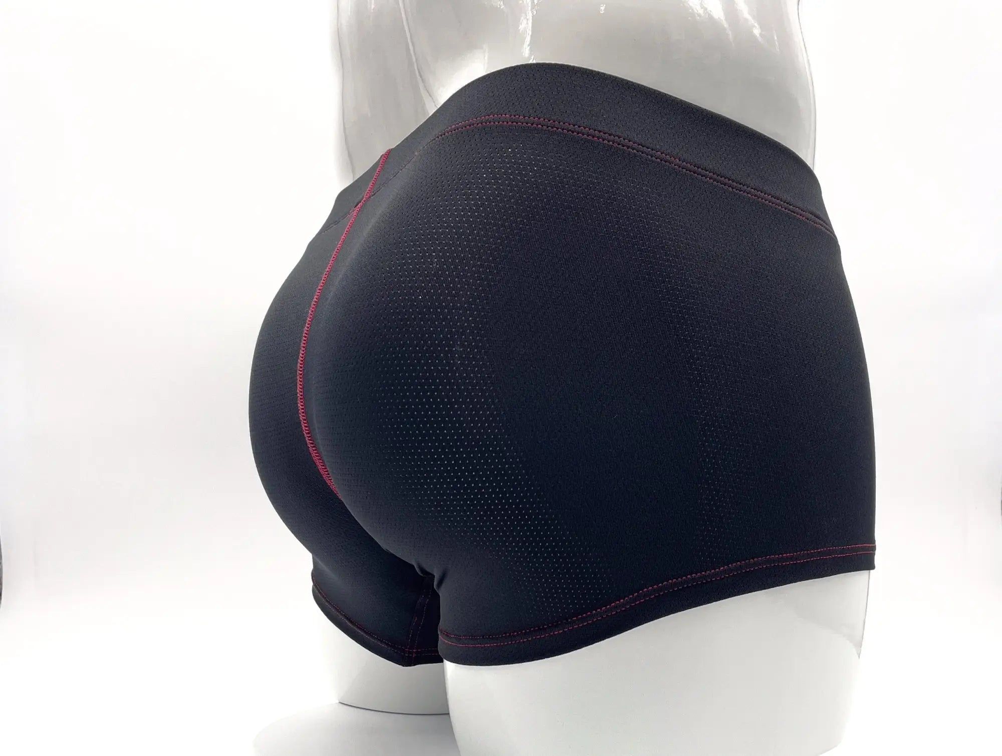 Black perforated boxer briefs on a mannequin with red contrast stitching, shown from the back.