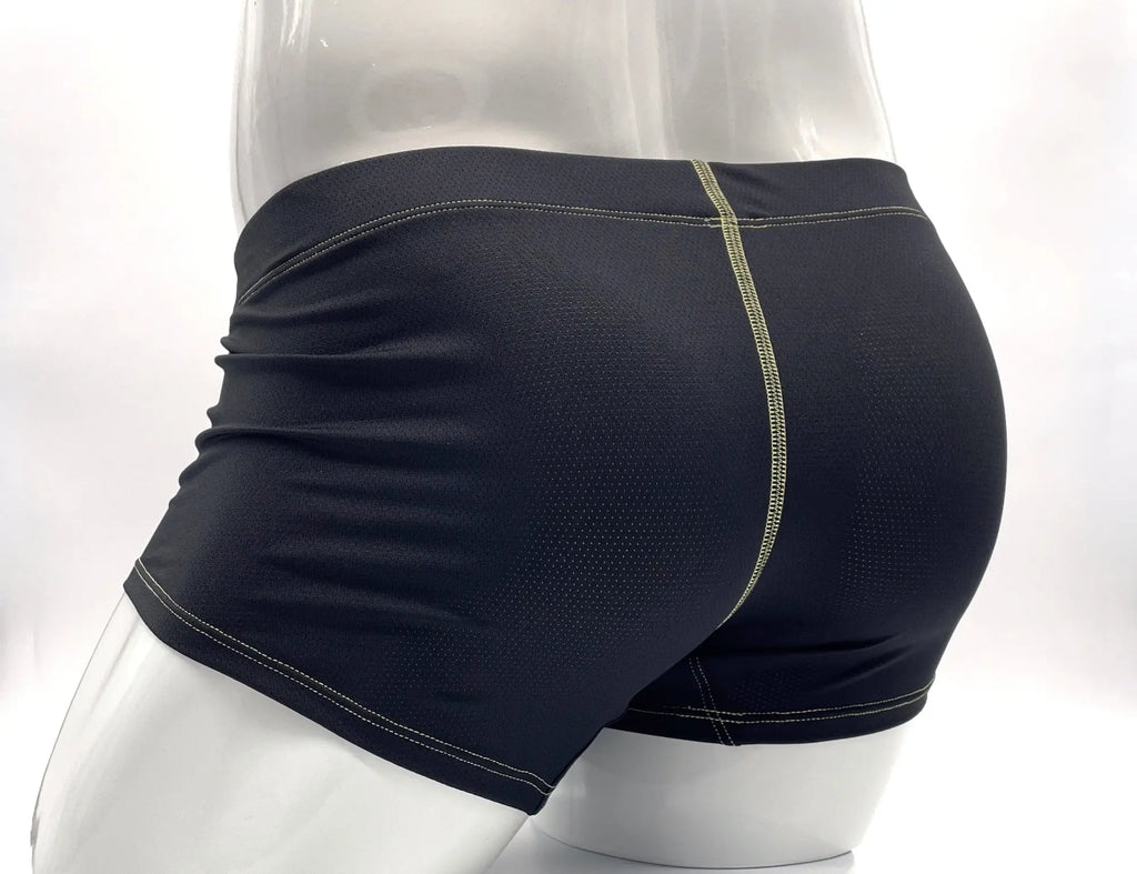 Black perforated boxer briefs on a white mannequin, featuring exposed yellow stitching details on the back and seams.