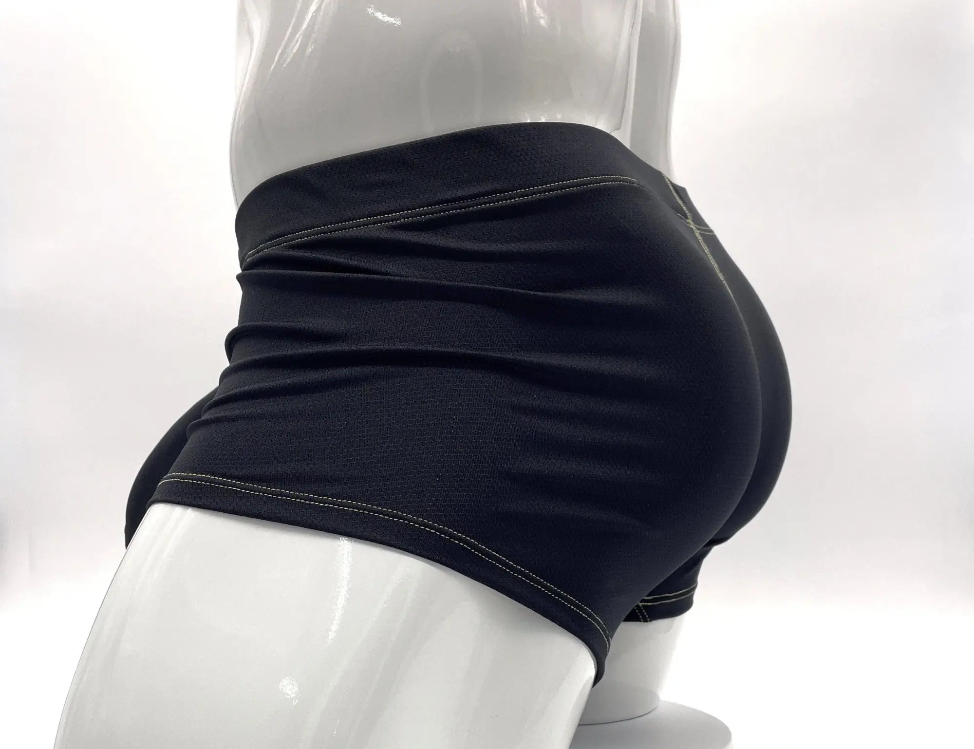 Black pouch boxer briefs on a white mannequin, featuring prominent yellow contrast stitching and textured fabric.