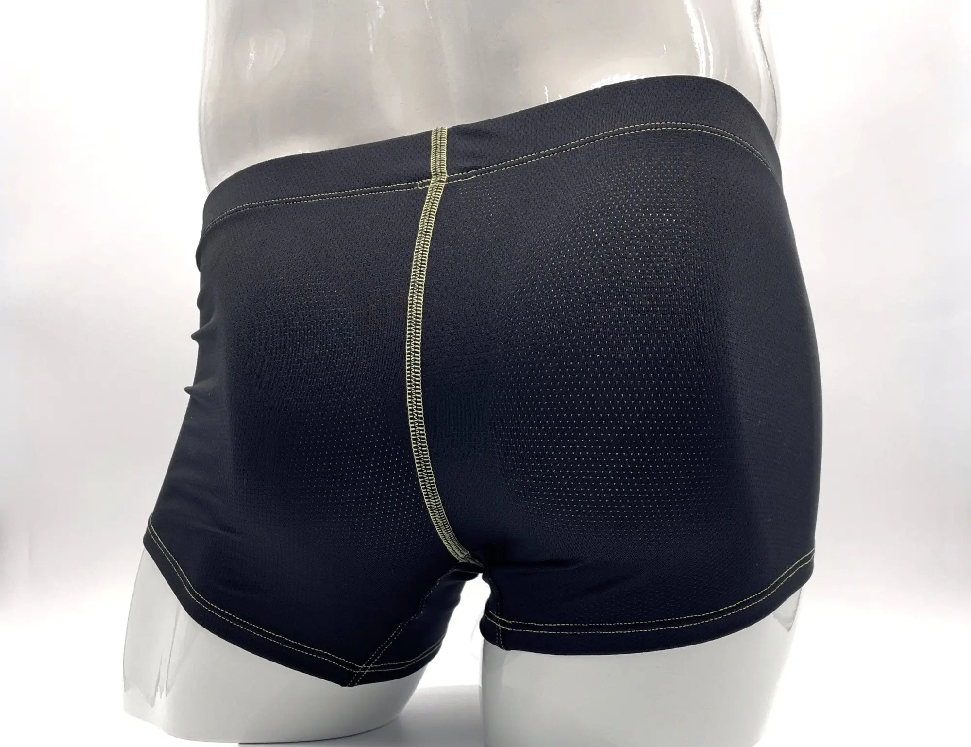 Black mesh boxer briefs on a mannequin, featuring prominent yellow contrast stitching along the seams.