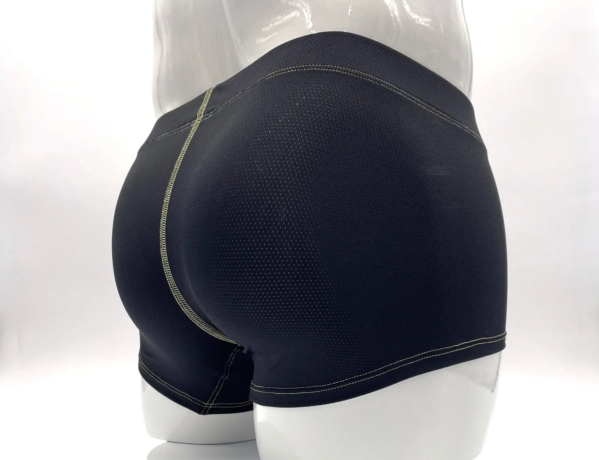 Back view of black mesh boxer briefs on a mannequin, featuring prominent yellow contrast stitching.