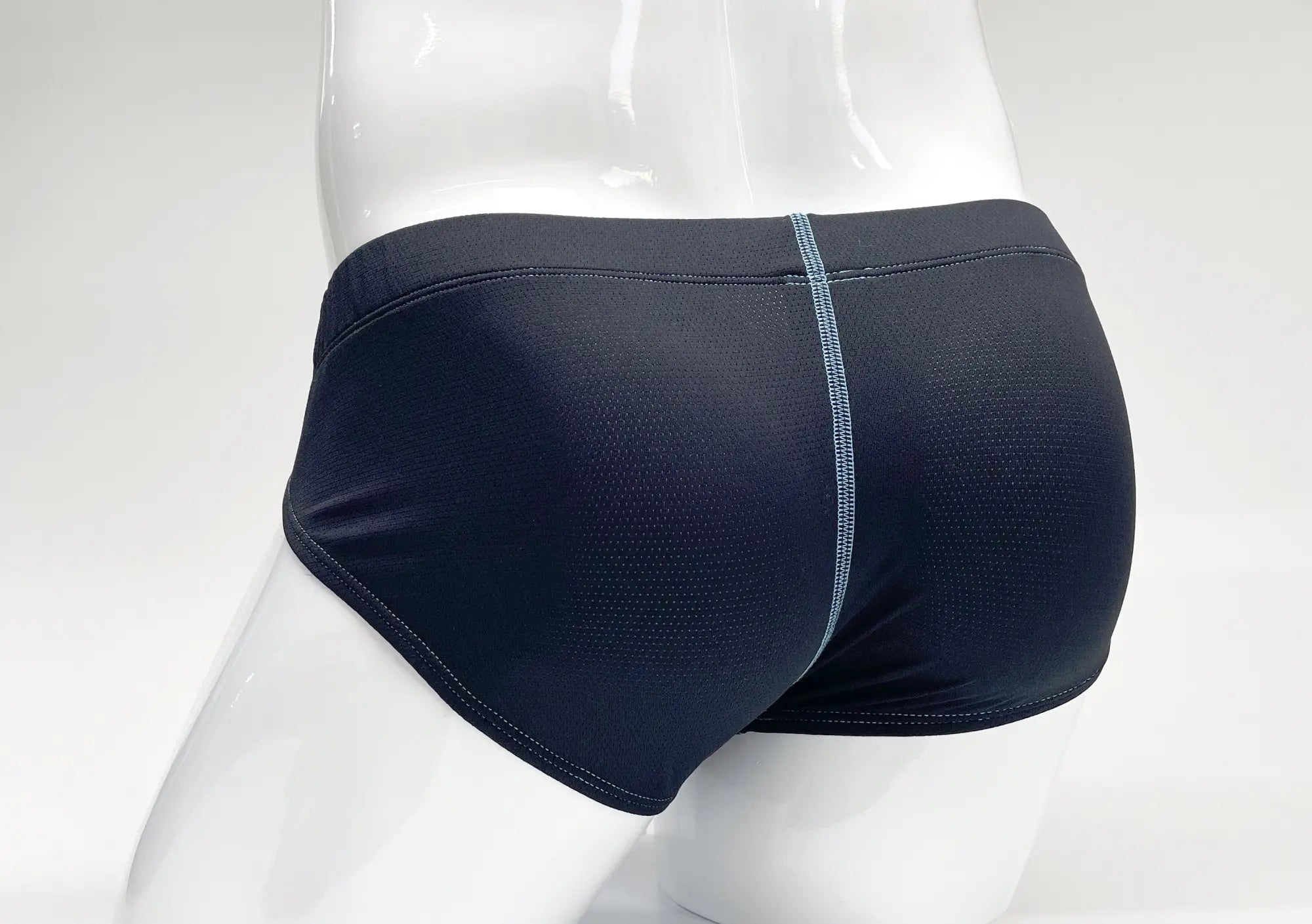 Dark blue perforated fabric pouch briefs on a white mannequin, featuring a vertical light blue stitched center seam.