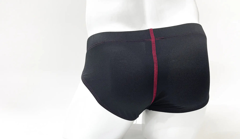 Black perforated pouch brief on a mannequin, featuring a prominent vertical red stitch seam down the center back.